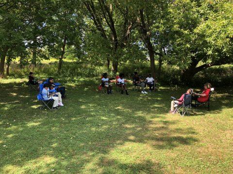 Students enjoy the shade of their outdoor classroom during read-a-loud time.